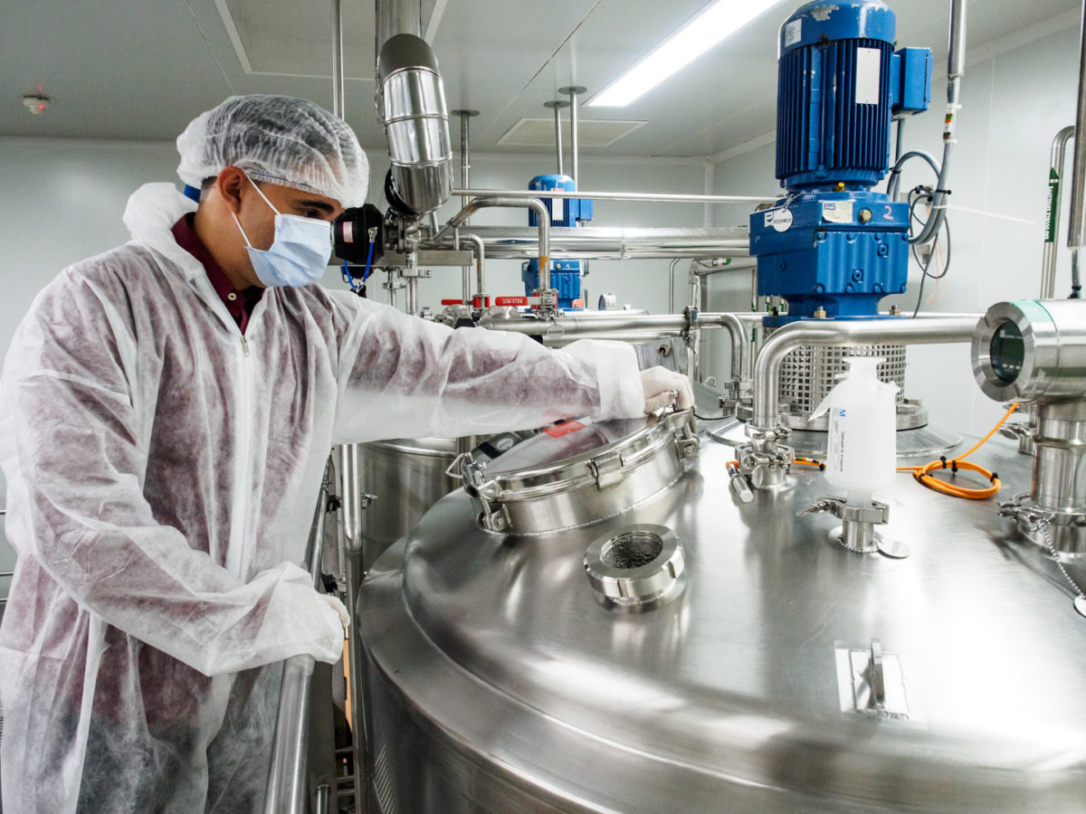 Entreprise pharmaceutique Saidal. Alger (Algérie), 2015. Photographie industrielle: un technicien en équipement stérile manipule le réservoir d'un réacteur. Photographie réalisée par le photographe d'entreprise et photographe industriel Grégory Dziedzic.