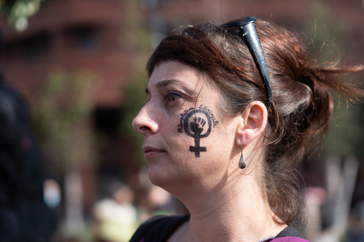 Portrait de profil d'une manifestante sur le visage de laquelle est dessiné le logo poing levé de la lutte féministe avec l'inscription "Révolution féministe" lors de la manifestation pour la journée sur les droits des femmes. Toulouse, 8 mars 2021.