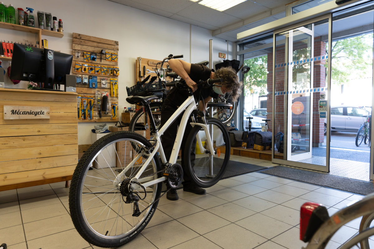 Une employé de la boutique de réparation de vélo Mécanicycle prend en charge un vélo pour le réparer. Toulouse, le 23 avril 2021.