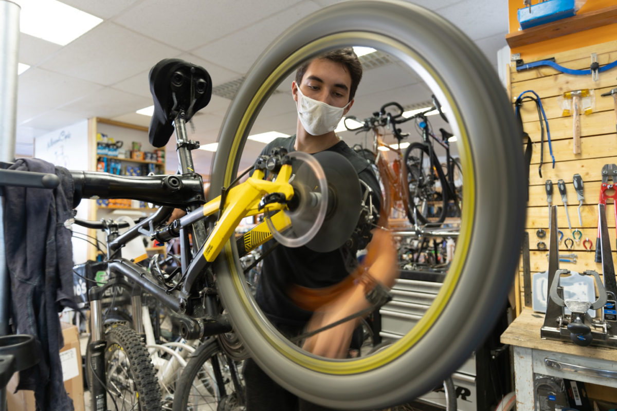 Un employé de la boutique de réparation de vélo Mécanicycle vérifie le mouvement d'une roue de vélo. Toulouse, le 23 avril 2021.