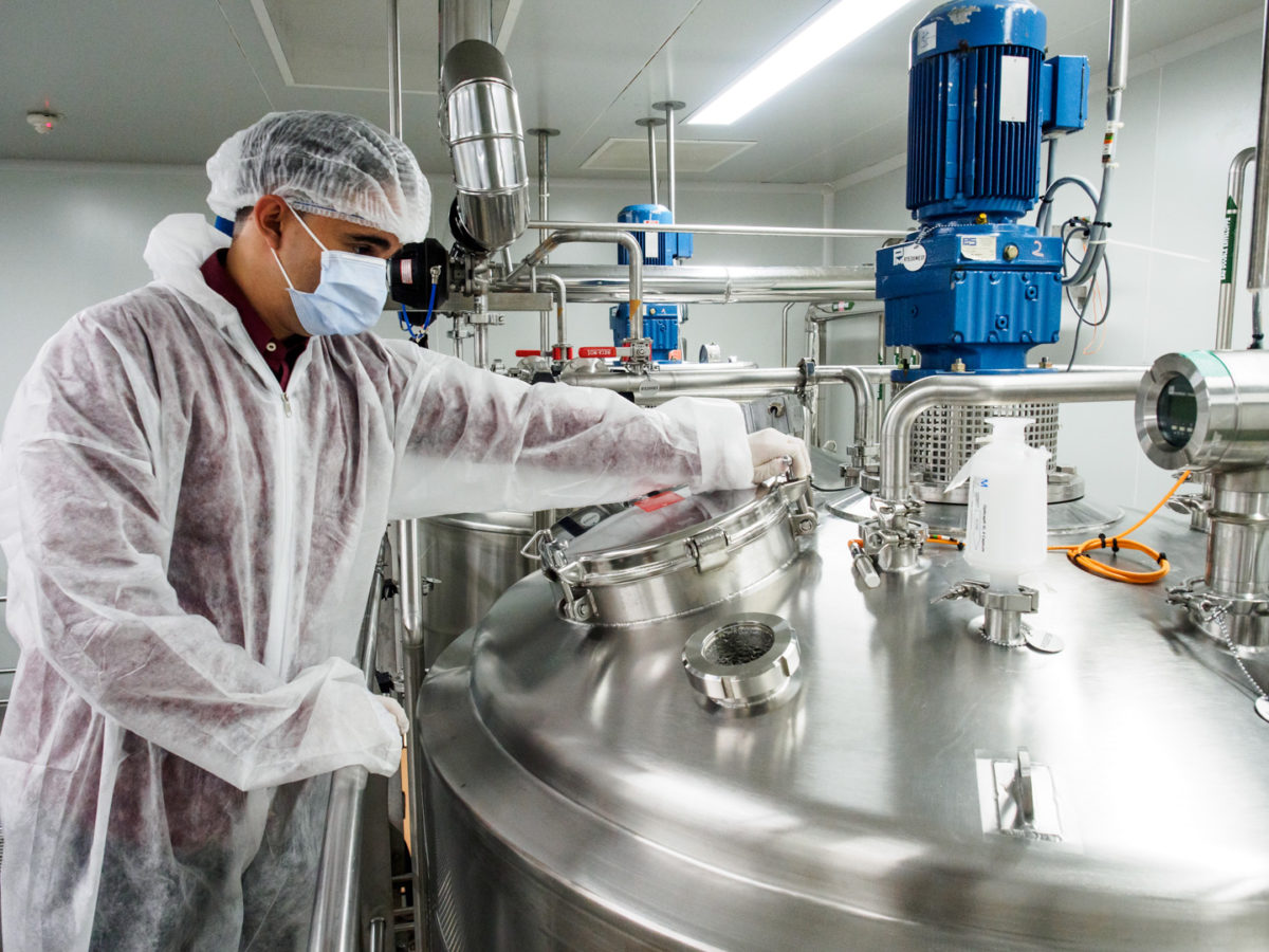 Photographie industrielle: un technicien en équipement stérile manipule le réservoir d'un réacteur. Photographie réalisée par le photographe d'entreprise et photographe industriel Grégory Dziedzic.